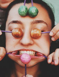 Cropped hands covering woman face with lollipops