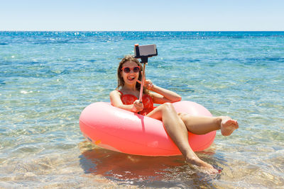 Portrait of woman photographing sea