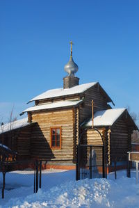 Low angle view of church against clear blue sky during winter