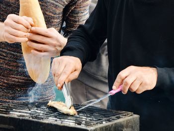 Midsection of men preparing food on barbecue