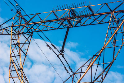Low angle view of electricity pylon against blue sky