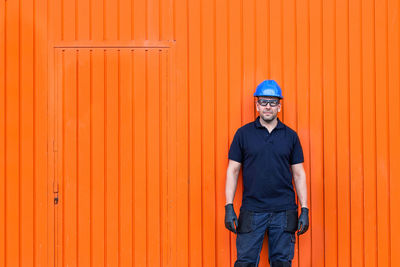 Portrait of smiling man standing against orange wall