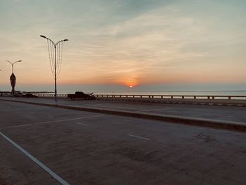 Street by sea against sky during sunset