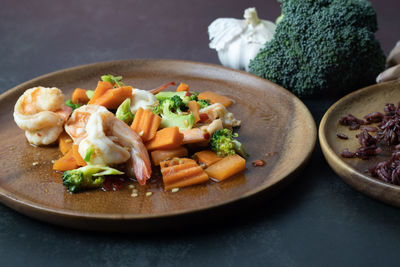 Broccoli stir fried with shrimp and rice on a black background