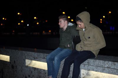 Friends sitting on retaining wall at night