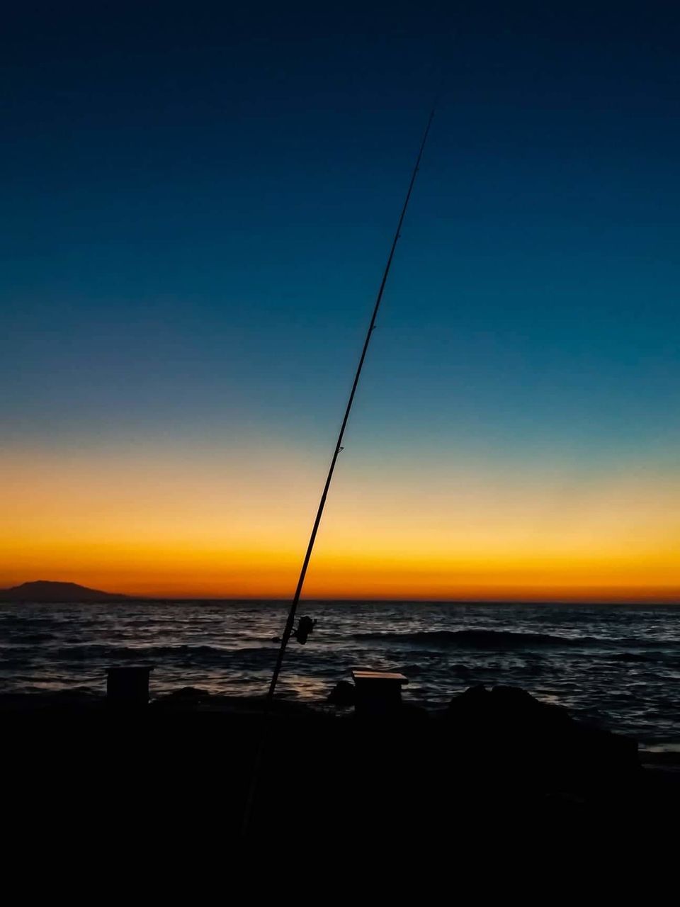 sky, sea, water, horizon, scenics - nature, sunset, horizon over water, beauty in nature, tranquility, tranquil scene, silhouette, nature, clear sky, no people, land, blue, fishing rod, copy space, beach, outdoors