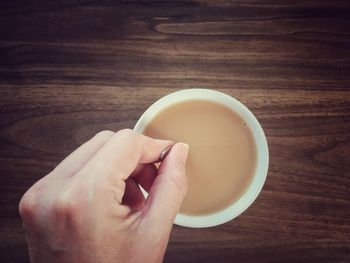 High angle view of hand holding drink on table