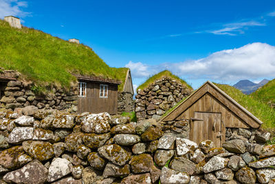 Stone wall of house and building against sky