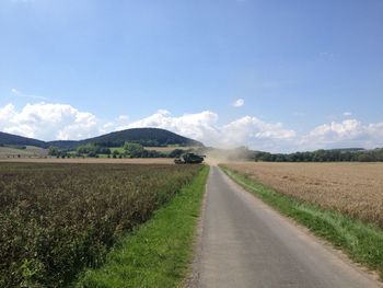 Road amidst field against sky