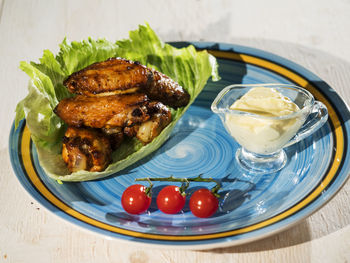 High angle view of chicken wings with cream and cherry tomatoes in plate on table