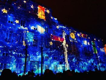 Low angle view of crowd at illuminated building in city at night