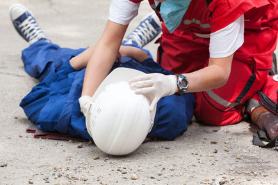 Paramedic performing cpr on person lying on street