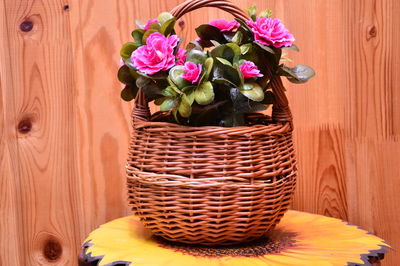 Close-up of pink flowers in basket on wooden table