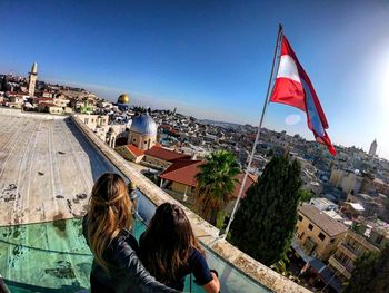 Rear view of people looking at cityscape against sky