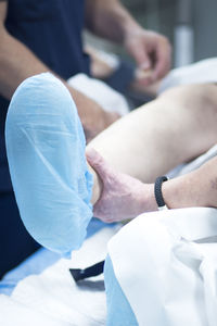 Midsection of doctor holding patient leg in operating room
