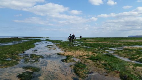 People walking at beach against sky