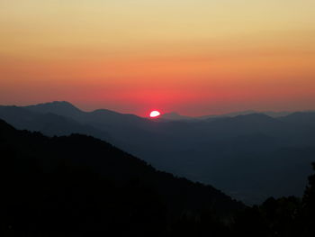 Silhouette mountains against orange sky during sunset