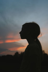 Young girls silhouette against a sunset sky