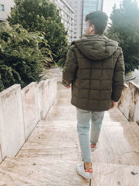 Rear view of man walking on snow covered walkway