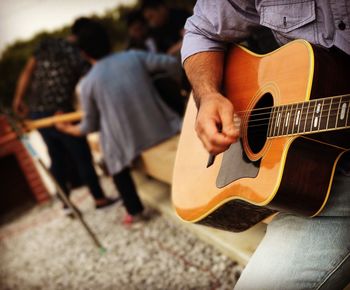 Midsection of man playing guitar