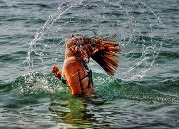 Young woman tossing hair in sea