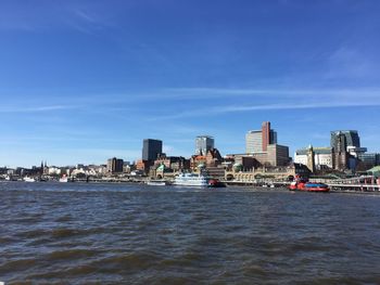 Sea by buildings against blue sky