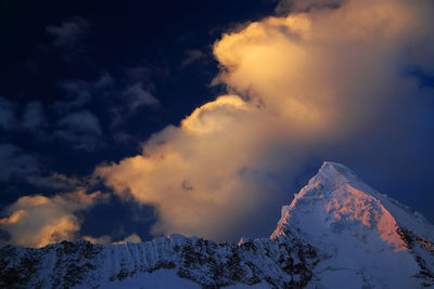 Scenic view of snow covered mountains against cloudy sky