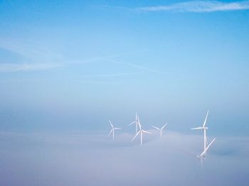 Wind turbines on landscape against blue sky