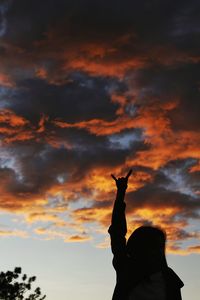 Low angle view of silhouette statue against dramatic sky