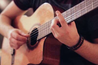 Midsection of man playing guitar