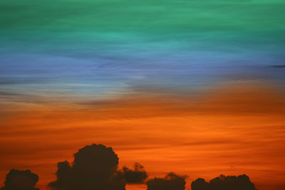 Low angle view of silhouette trees against dramatic sky