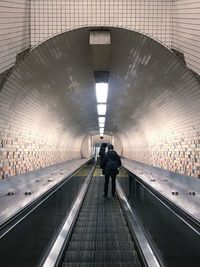 Rear view of people walking on escalator in subway