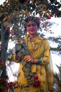 Portrait of smiling young woman standing against trees