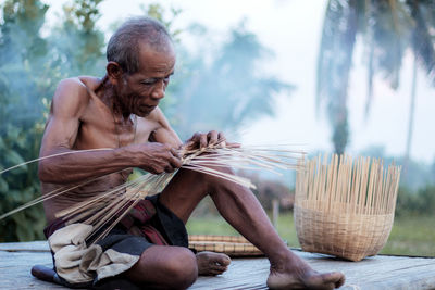 Man sitting on wood against trees