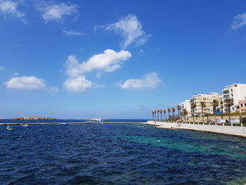 Scenic view of sea and buildings against blue sky