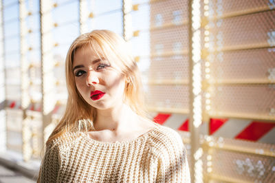 Portrait of young woman standing against wall