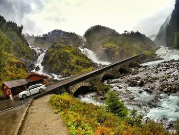 Scenic view of waterfall and mountains against sky