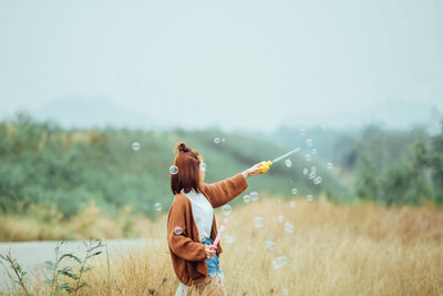 Rear view of people on field against sky