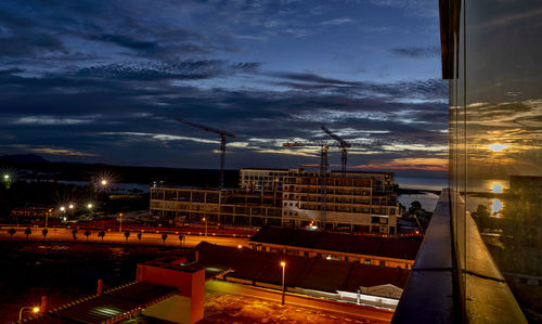 Illuminated buildings in city at sunset