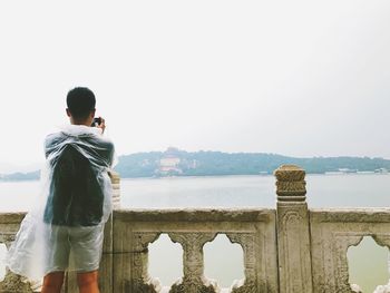 Rear view of woman photographing against sky