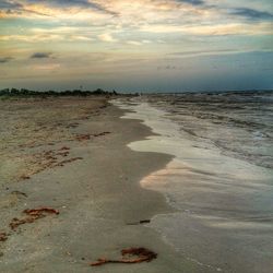 Scenic view of beach against cloudy sky