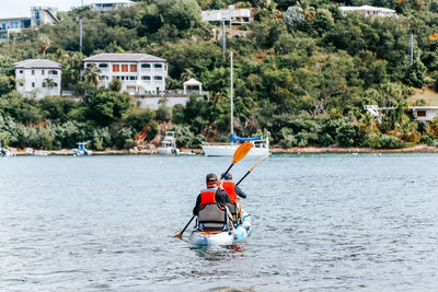 Man with umbrella on boat against trees