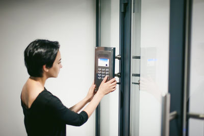 Woman pressing button on door at home