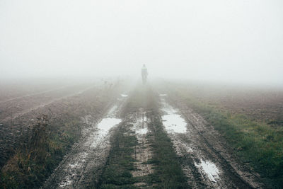 People walking on road against sky during foggy weather