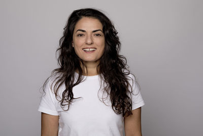 Portrait of smiling young woman against white background