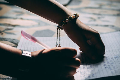 Cropped hands of woman writing in book on floor