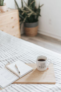 Coffee mug and planner on a tray in a minimalist bedroom