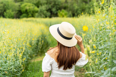 Rear view of woman wearing hat on field