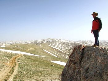 Rear view of man standing on mountain against clear sky