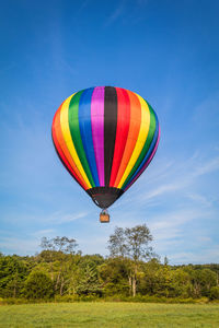 Hot air balloon flying over trees against sky